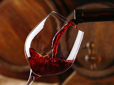 A tilted wine glass being filled from a bottle of red wine