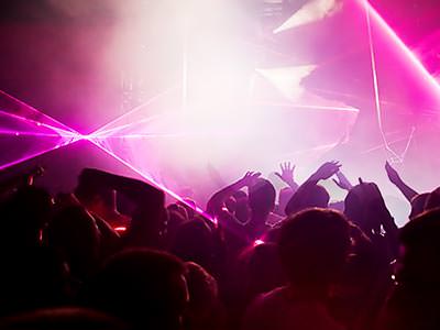 People dancing in a club to a backdrop of pink light