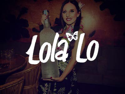 A woman in a lei garland, holding a large bottle of vodka in a club