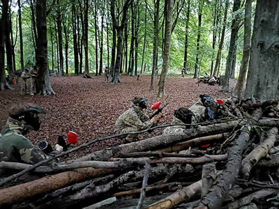Multiple people in a forest playing outdoor paintball