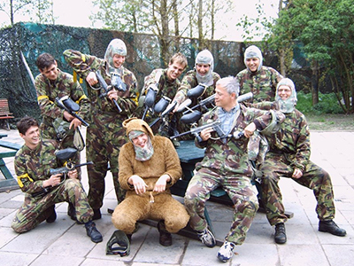 A group of men aiming paintball guns at a main dressed in a costume