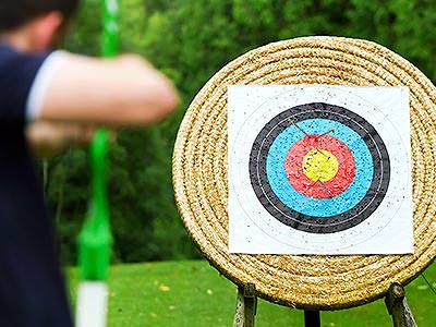 A main aiming a bow and arrow and a wicker archery target
