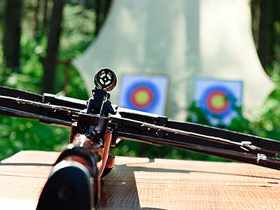 A crossbow laying on a table with two targets visible in the background