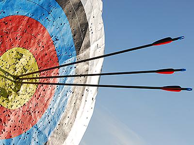 A large archery target with three arrows stuck in it