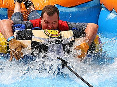 A man lying on his front and holding an inflatable surrounded by water
