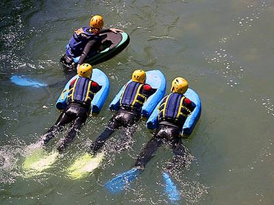 A group of people paddle through water, holding onto floats