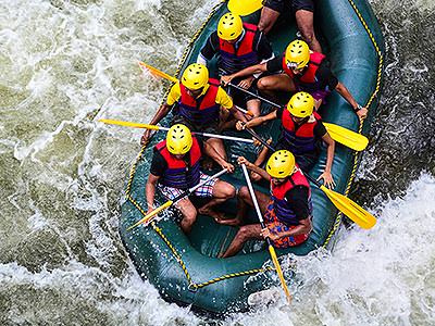 A bird's eye view of a white water rafting raft paddling through rapids