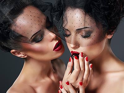 A woman feeding another woman a cherry, both are wearing veils