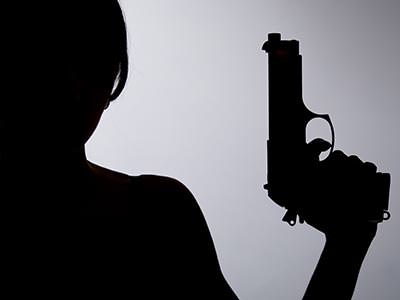 The silhouette of a person posing with a handgun