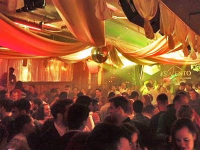 A view over a filled dance floor with white canvas above, and orange lighting