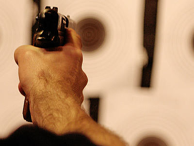A person's hand firing a gun, with the background out of focus 
