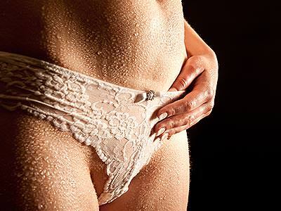 A woman wearing pale pink knickers with water droplets on her stomach and legs