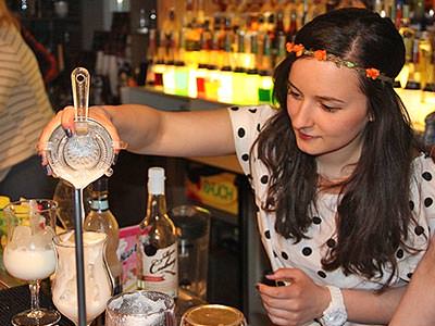 A woman pouring a cocktail into a glass