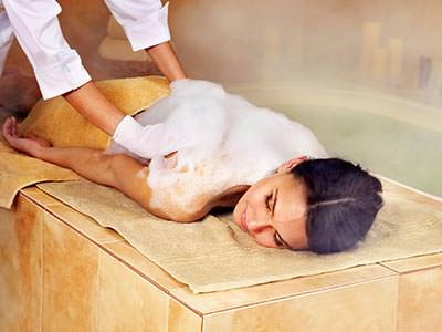 A woman lying forwards on a bed receieving a back massage