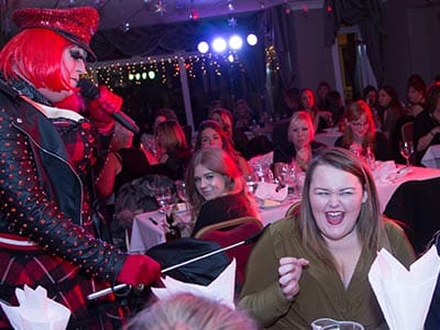 A man in drag singing into a microphone 