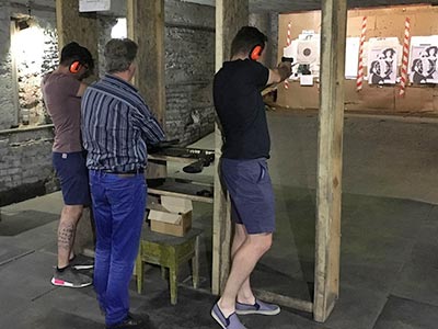 Two men with an instructor, aiming guns at a target - Rank #1