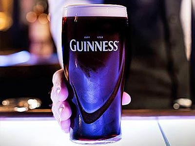 A man's hand holding a pint of Guinness