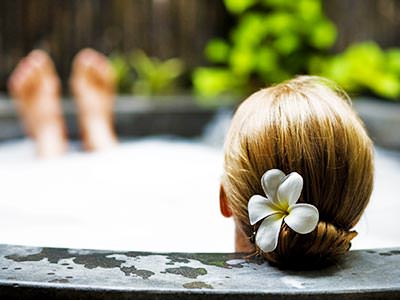 The back of a woman's head with a flower in her hair, lying back in an outdoor Jacuzzi