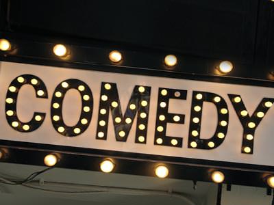 The word Comedy lit up by light bulbs