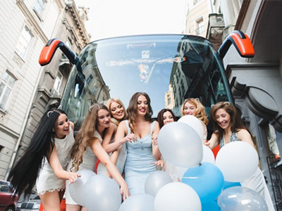 A group of girls outside of a party bus with silver, white and blue balloons in Benidorm