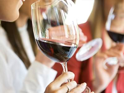 A woman holding a glass of red wine to her mouth
