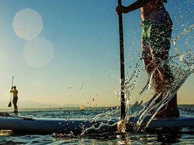 A man paddle boarding on a still ocean against a clear blue sky