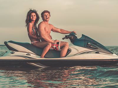 A woman and a man laughing and posing on a jet ski
