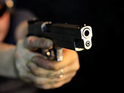 A pair of hands aiming a handgun past the camera