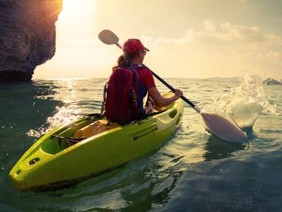 A woman heading out to sea on a kayak at sunrise