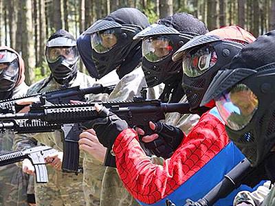 A line of people wearing overalls and full-face masks aiming AR15-style airsoft rifles