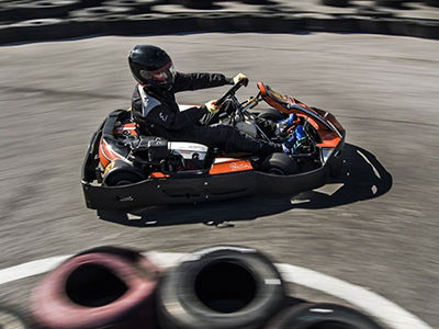 Two people racing in red go karts on an outdoor track