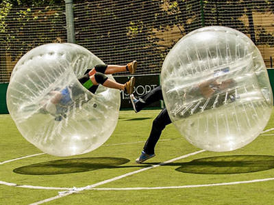 Two people bouncing off each other in inflated zorbs 