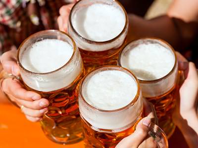 Four hands toasting with full beer steins