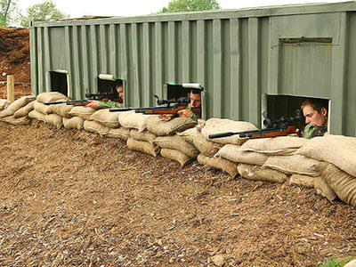 Men behind a barricade shooting air rifles