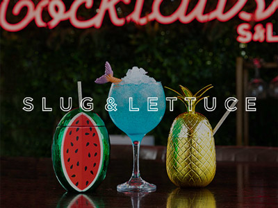 Three cocktails in fun glasses against a red neon sign with the slug and lettuce logo overlayed