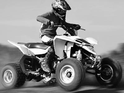A black and white image of a person driving a quad bike