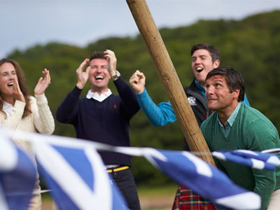 A man lifting a long wooden plank with people cheering him on beside him