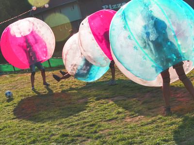 A group of people playing bubble football in red and blue inflatables