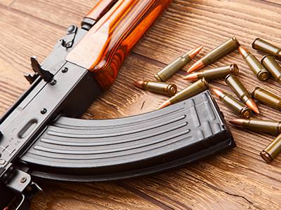 A kalashnikov rifle, on a table, next to bullets, on a table, next to bullets