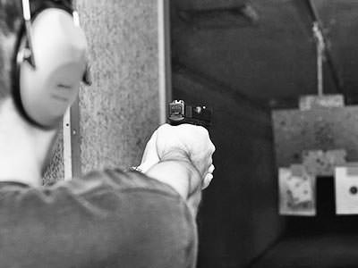 blakc and white image of man with hand gun at an indoor shooting range