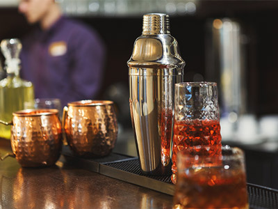 A cocktail shaker with two copper cups and a glass of liquids for the cocktail at a cocktail workshop in Prague