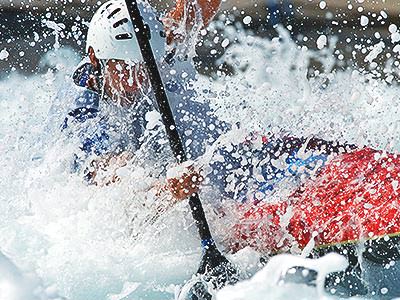 A person paddling a kayak through foamy rapids