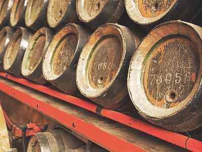 A stack of wooden barrels on a red shelf
