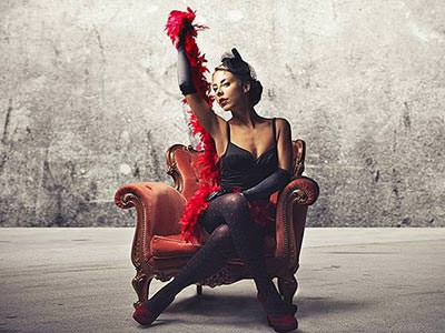 A woman sitting in a leather chair, posing with a red feather boa