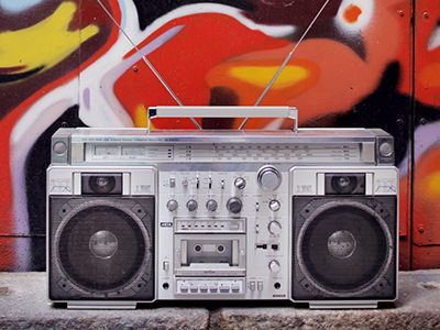Silver boombox on a floor, in front of colourful graffiti