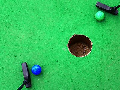 Two golf balls near a hole