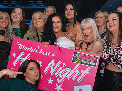 People dancing on a dancefloor holding a Hen Night sign
