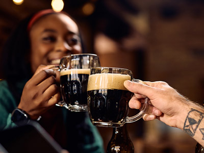 A woman clinking a pint of Guinness with someone else on a bar crawl in Dublin
