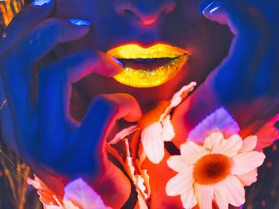 Close up of a woman's face with yellow lips, to a blue backdrop