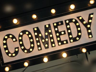 comedy sign lit up in stage lights